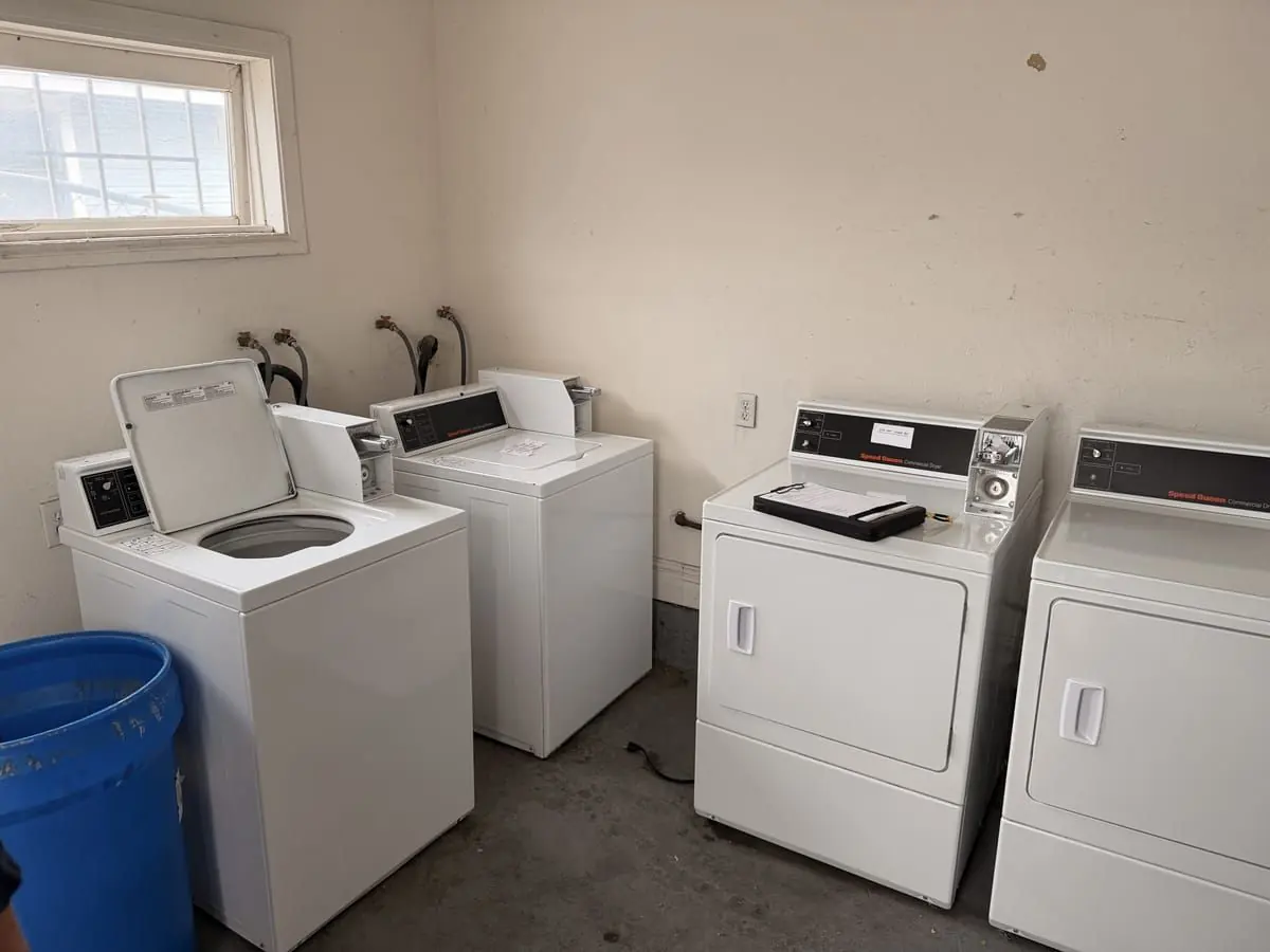 A tired apartment laundry room with older mismatched machines before Art's took over the account